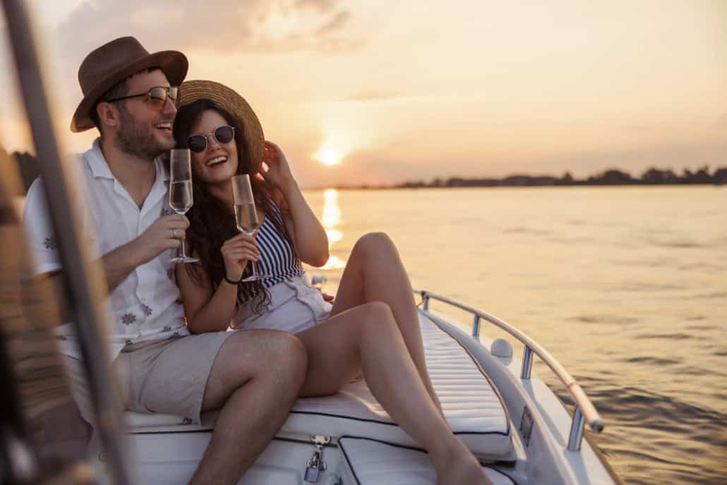 Pärchen umarmt sich und trinkt Champagner auf einem Boot Der erste gemeinsame Urlaub